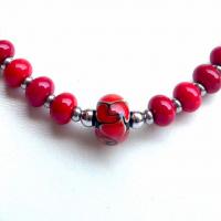 Detail de la perle centrale de la collection fleur en spirale rouge et noir du collier de perles de verre vendu en ligne sur notre site