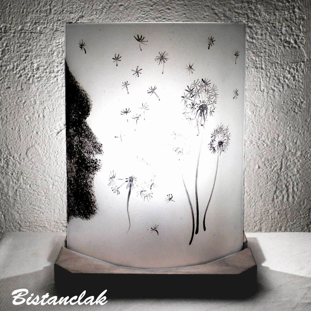 Lampe artisanale noire et blanche au dessin d'un souffle sur des fleurs de pissenlit